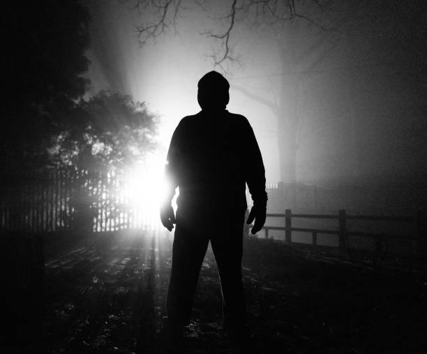 istock Sinister silhouette man lurking in forest at night 1305273512