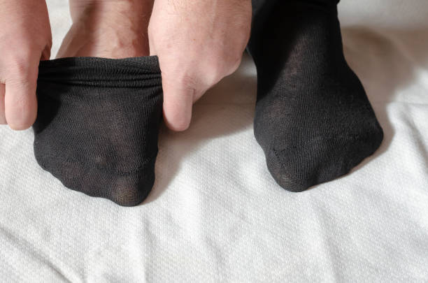 istock An adult man's hands put on new socks. 1305273549