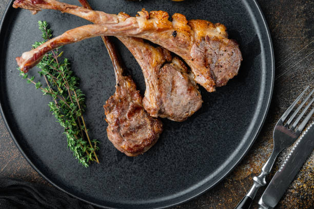 istock Barbecue dinner. Grilled lamb meat chops with onion and thyme, on plate, on old dark rustic background, top view flat lay 1305273878