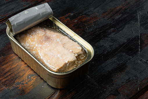 Canned wild Trout set, in tin can, on old dark  wooden table background, with copyspace  and space for text