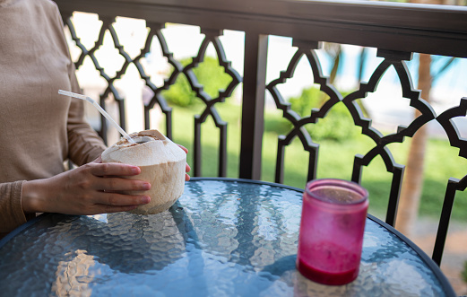 Woman having fresh coconut on the balcony with tropical vibe