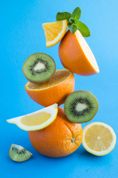 istock Oranges, lemon and kiwi stacked pyramid on the blue background 1305277124
