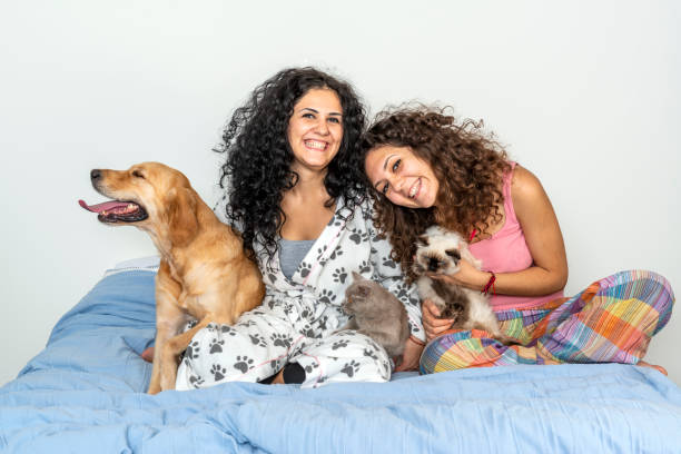 Sisters playing with their pets on bed in the morning