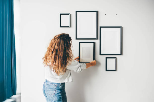 Woman hanging a frame on a wall. Woman hanging a frame on a wall. vehicle interior photos stock pictures, royalty-free photos & images