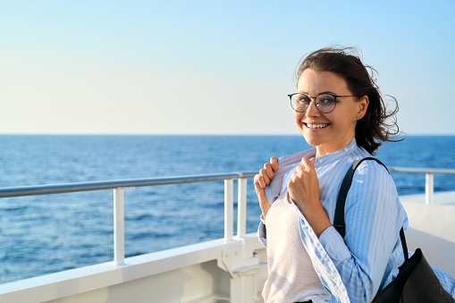 Feliz mujer de mediana edad en cubierta de crucero, copiar espacio photo
