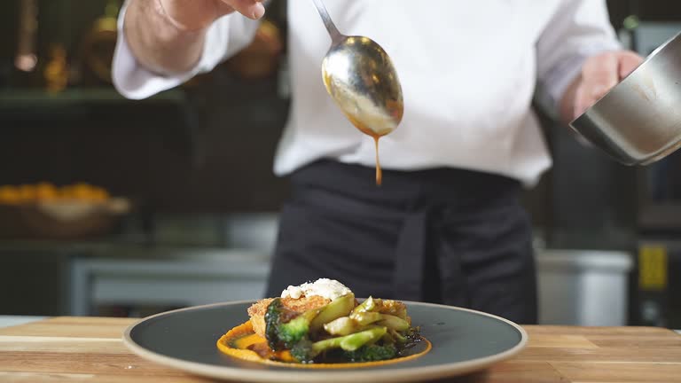 Close-up of a gourmet dish, the chef pours sauce over cutlets with pumpkin puree and broccoli on a plate
