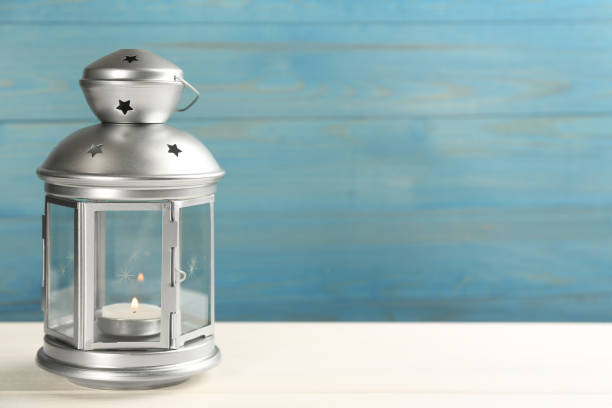 istock Beautiful decorative Christmas lantern with burning candle on white wooden table. Space for text 1305282067