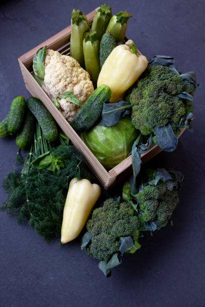 istock Vegetable basket. Fresh vegetables on the table black background. Set of food delivery box. Broccoli, cabbage, eggplant, white cabbage, cucumber, dill, cauliflower. Stilllife top view 1305282425