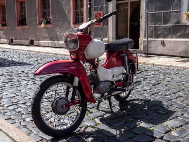 Retro motorcycle concept. Red vintage bike in field. Retro style photo with noise, square crop and copy space.
