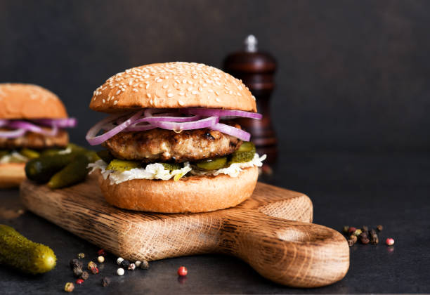 Homemade grilled burger with beef, cucumber, salad and onions. With copy space. stock photo