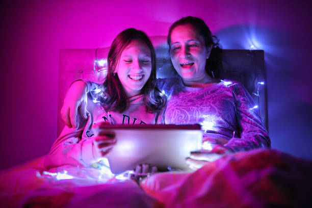 istock Mother and daughter watching video from tablet under LED light 1305284692