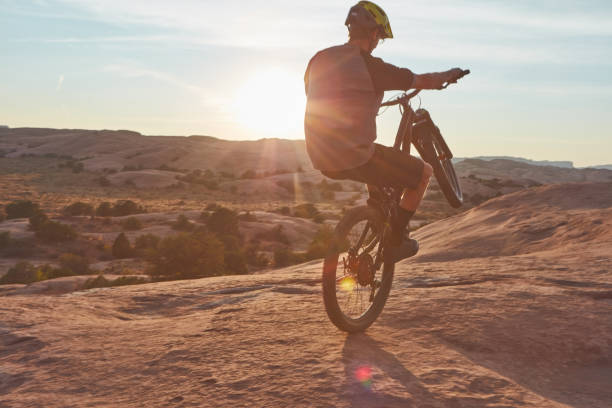 Time flies when you’re riding a bike Full length shot of a young male athlete popping a wheelie while mountain biking in the wilderness bicycle stunts stock pictures, royalty-free photos & images