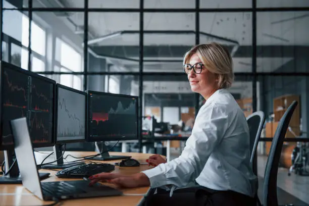 Female stockbroker in formal clothes works in the office with financial market.