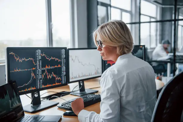 Female stockbroker in formal clothes works in the office with financial market.