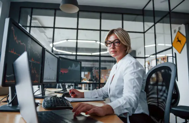 Female stockbroker in formal clothes works in the office with financial market.