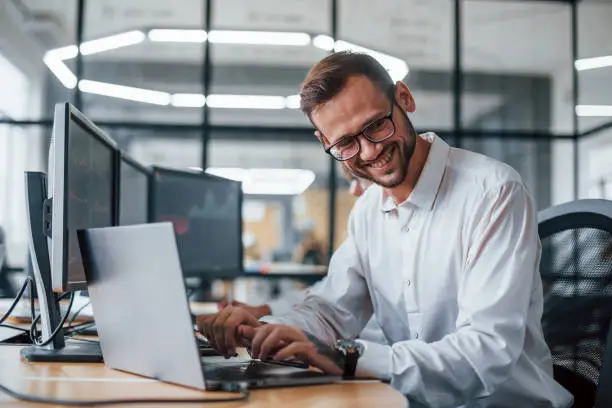 Male stockbroker in formal clothes works in the office with financial market.