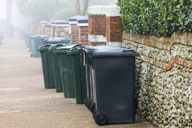 Wheelie Bins Wheelie bins on a pavement waiting for rubbish collection, UK. overflowing trash dumpster stock pictures, royalty-free photos & images