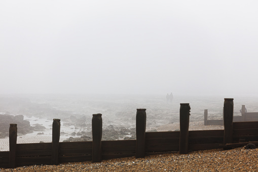 Wooden gutters on a pebbly beach on the Eastbourne coast on a foggy day