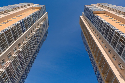 Two towers. Facades of new two tall buildings on a background of blue sky, bottom view. Construction industry