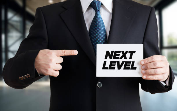 istock Businessman shows a card with the message next level. Progress, growth, development or improvement in business career 1305291155