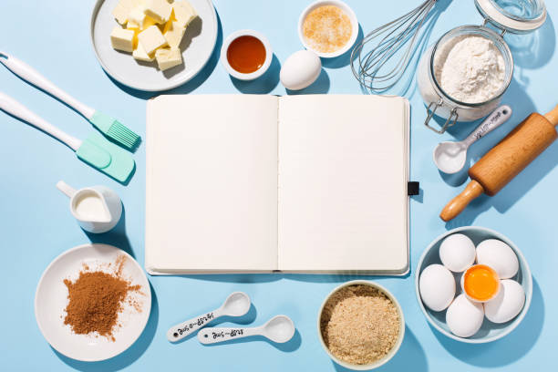istock Cooking baking background with empty cookbook, ingredients, fresh eggs, spices and utensils on blue table. 1305291171