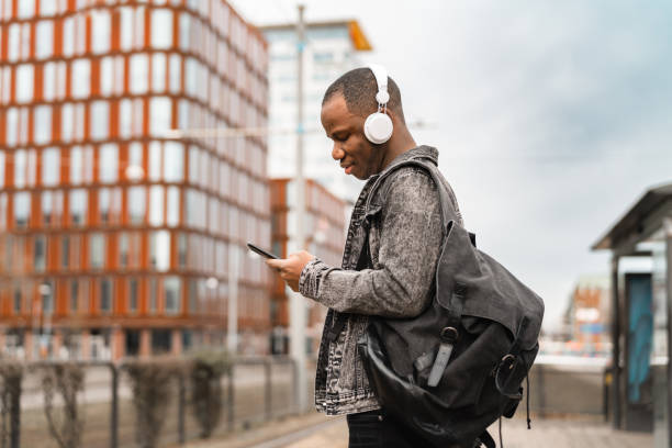 Student on his way home from university with smartphone in hand