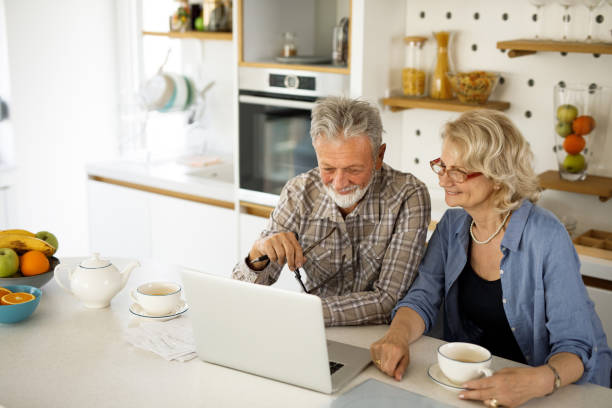 istock Senior couple checking their bills using laptop in the kitchen 1305292020