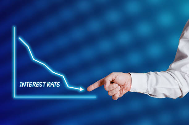 Businessman hand points to the word interest rate with a decreasing chart or graph.