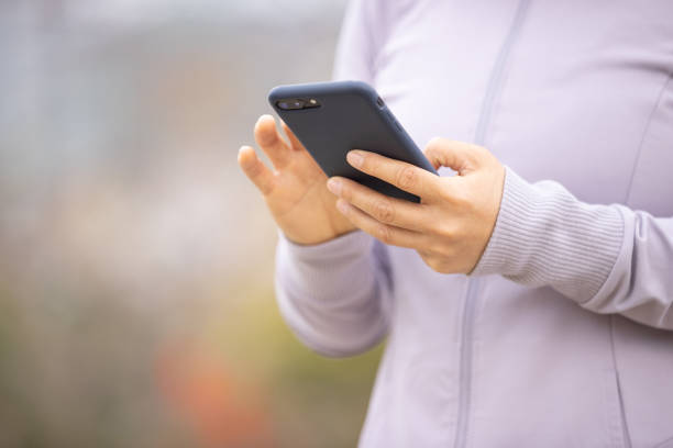 istock Asian woman using smartphone outdoors 1305294123