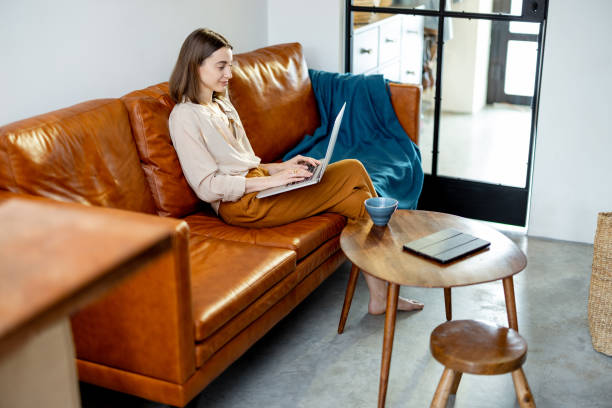 istock Woman sitting on the sofa at home with laptop 1305295232