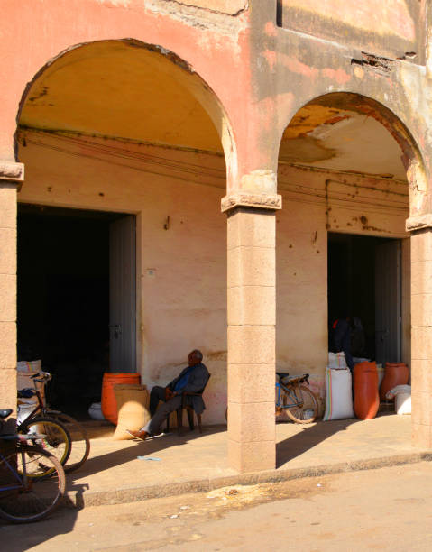Asmara, Eritrea: a grain merchant waits in the shade - market gallery along Barentu Street - many shops have no signs or markings.