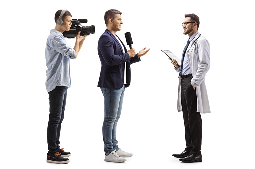 Full length profile shot of a reporter interviewing a doctor and a cameraman recording isolated on white background