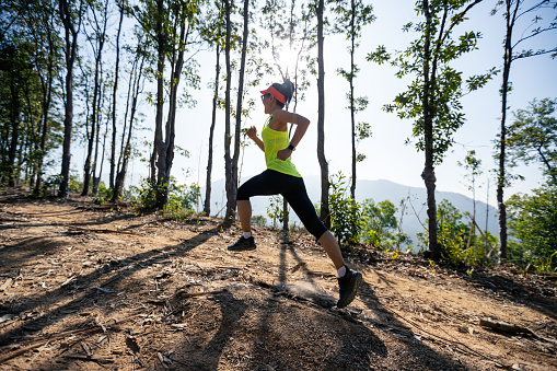 Fitness woman trail runner running on sunrise tropical forest mountain peak