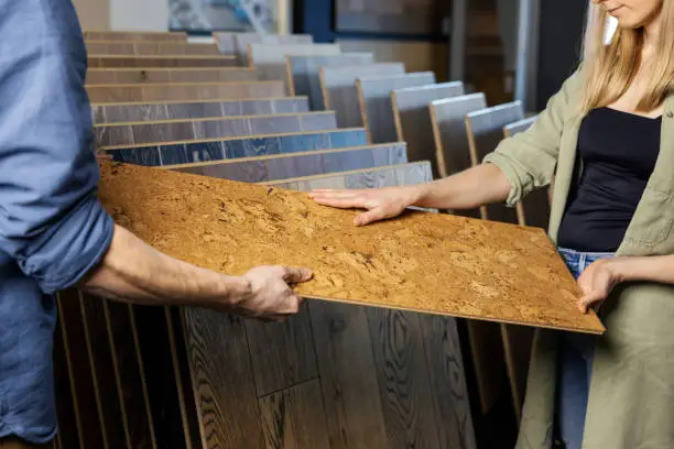 Photo of young couple choosing cork floor for home improvements in flooring shop