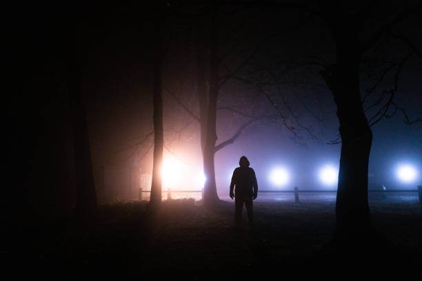 istock Sinister silhouette man lurking in forest at night 1305302270