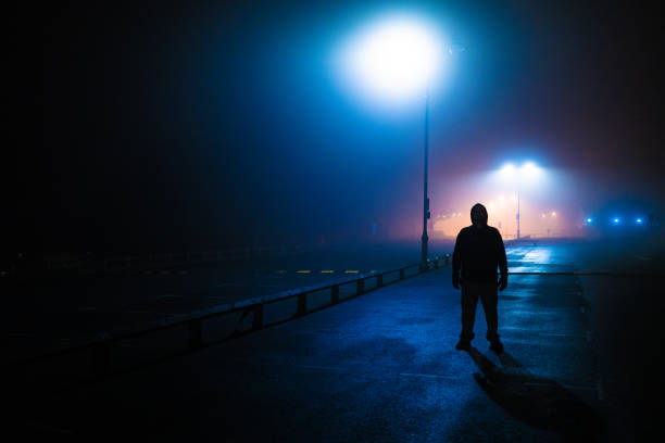 homme sinistre de silhouette se cache dans le stationnement désert - mauvais présage photos et images de collection