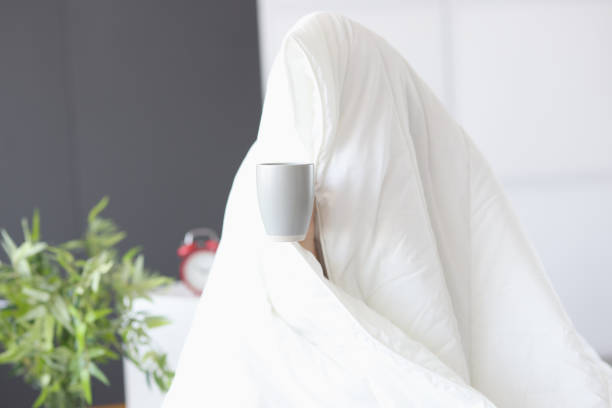 Man sitting under blanket with cup of coffee