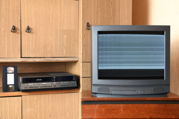 istock An old black TV with noise and interference on the screen and a VCR against the backdrop of old furniture from the 1980s and 1990s. 1305308251