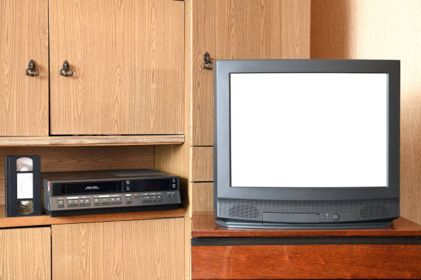 istock An old black TV with a white isolated screen for adding images and a VCR against old furniture from the 1980s and 1990s. 1305308301