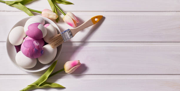 istock Easter card. Eggs, brush, paint, a bouquet of tulips on a white table. Top view, copy space 1305308789