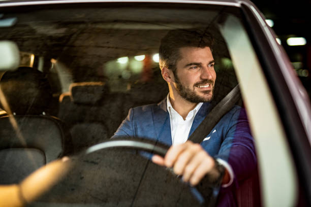istock Handsome man driving a car in public garage. 1305312891
