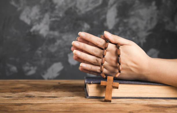 istock woman holding cross on Bible 1305313701