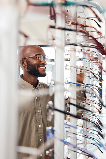 Shot of a young man buying a new pair of glasses at an optometrist store