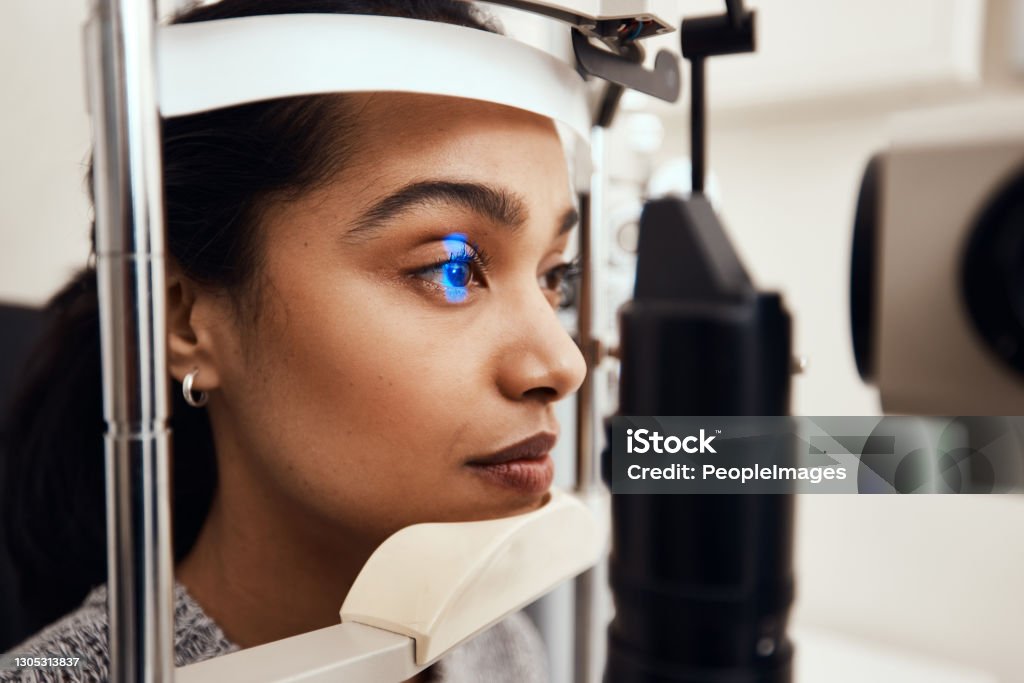Keep as still as possible Shot of a young woman getting her eye’s examined with a slit lamp Eye Exam Stock Photo