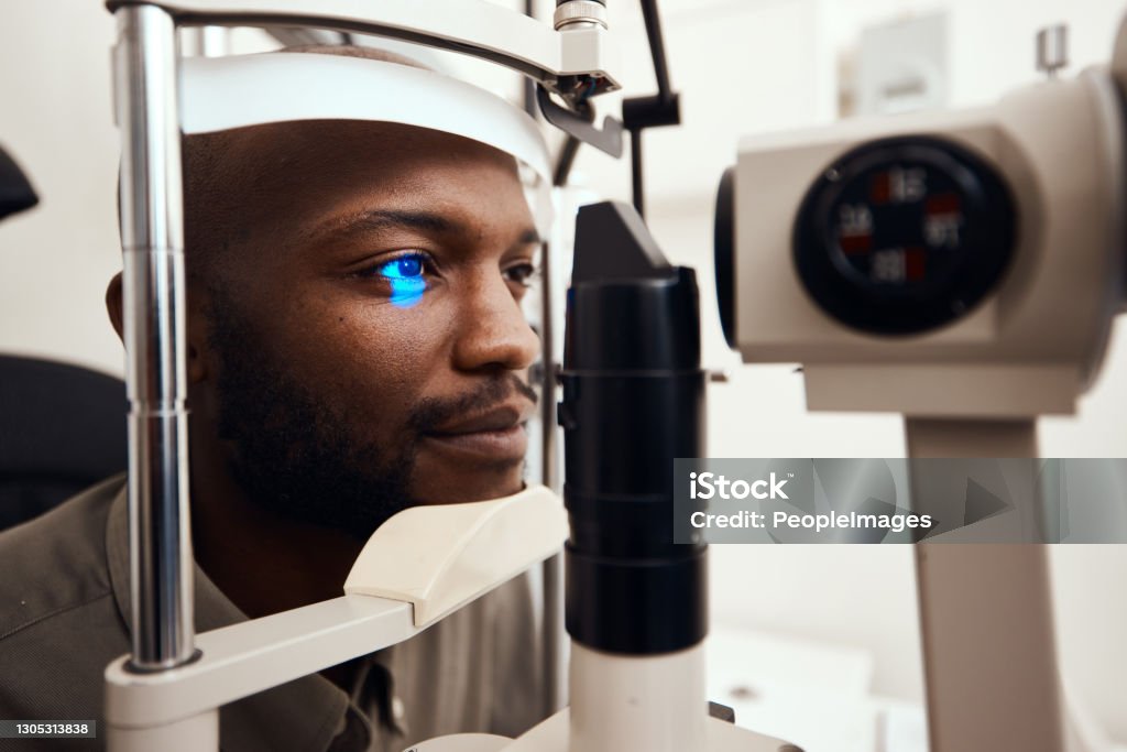 Life is a lot brighter with better vision Shot of a young man getting his eye’s examined with a slit lamp Eye Exam Stock Photo
