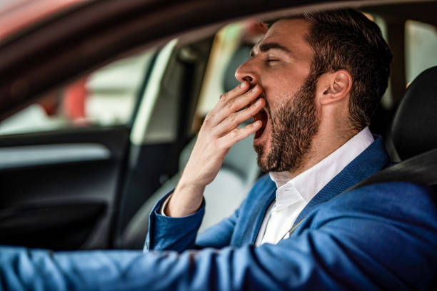 um homem dirigindo um carro e bocejando. - yawning - fotografias e filmes do acervo