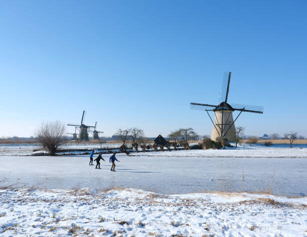 people skate on the ice near kinderdijk with al lot of windmills in holland on sunny winter day - alblasserwaard imagens e fotografias de stock