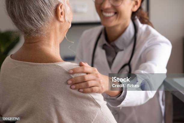 Close Up Back View Smiling Doctor Touching Mature Patient Shoulder Stock Photo - Download Image Now