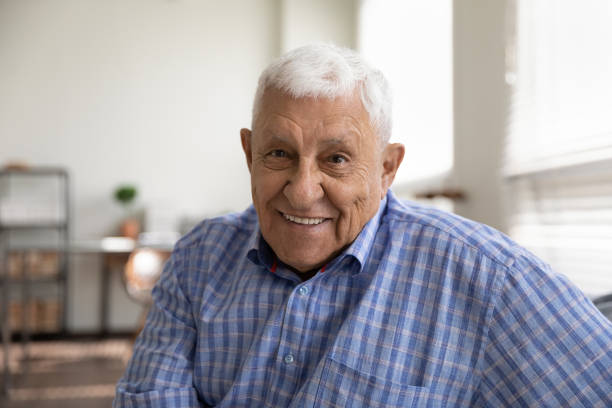 Head shot portrait smiling mature man looking at camera Head shot portrait smiling mature man looking at camera, happy grandfather chatting with relatives online, making video call, senior blogger shooting recording video, elderly teacher working online 80 89 years stock pictures, royalty-free photos & images