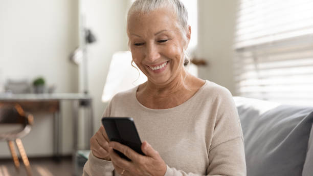 istock Close up overjoyed mature woman using phone at home 1305317745